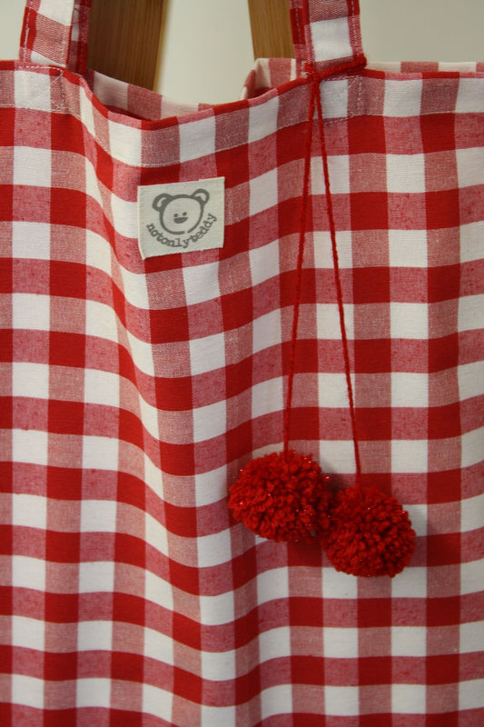 dettaglio pom pon su borsa donna shopping a quadri rossi