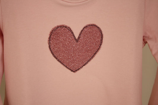 Dettaglio di felpa rosa con cuore di maglina glitterata rosa