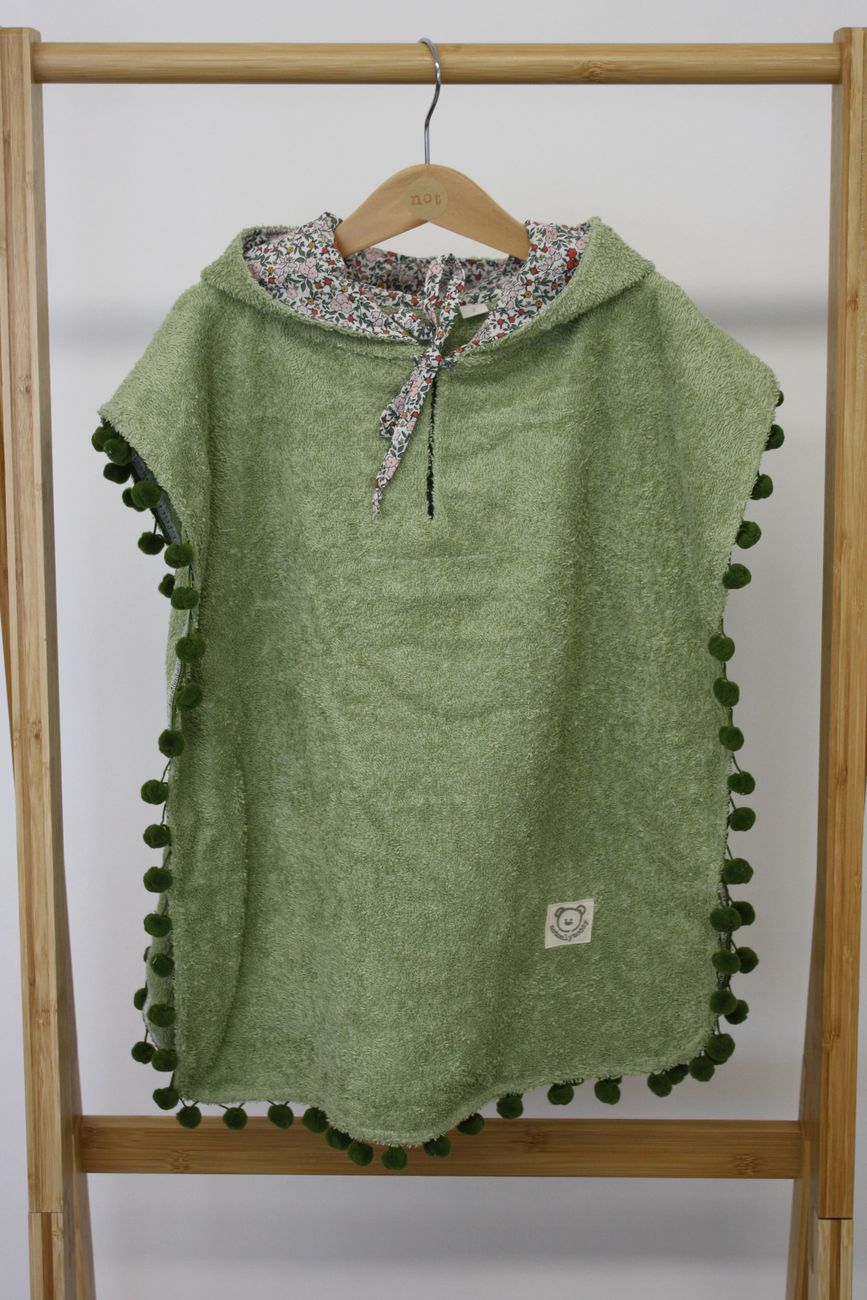 poncho verde appeso, bordato con pompon verdi, cappuccio foderato a fiorellini