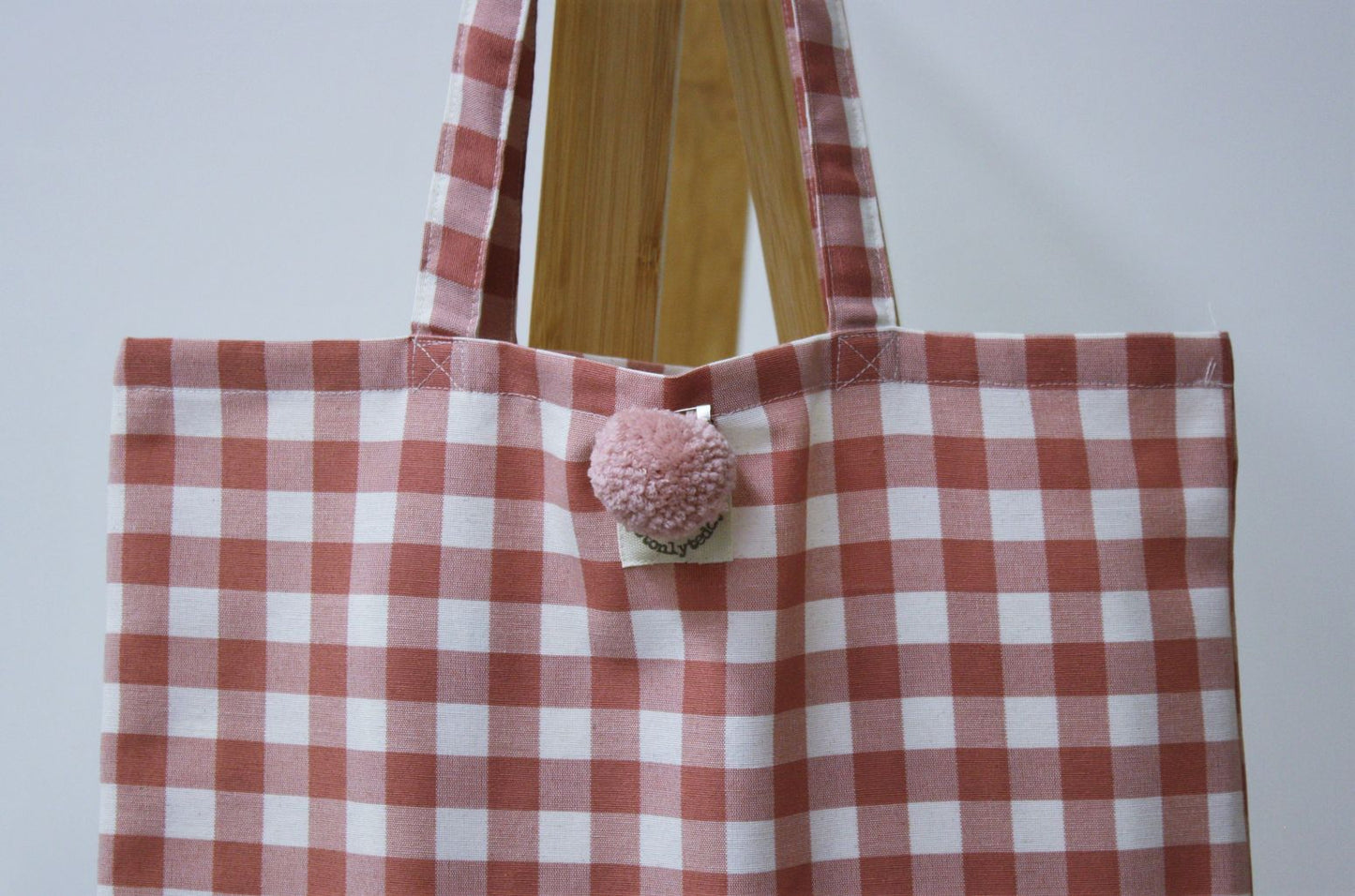 dettaglio spilla pon pon rosa su shopper donna quadri rosa antico