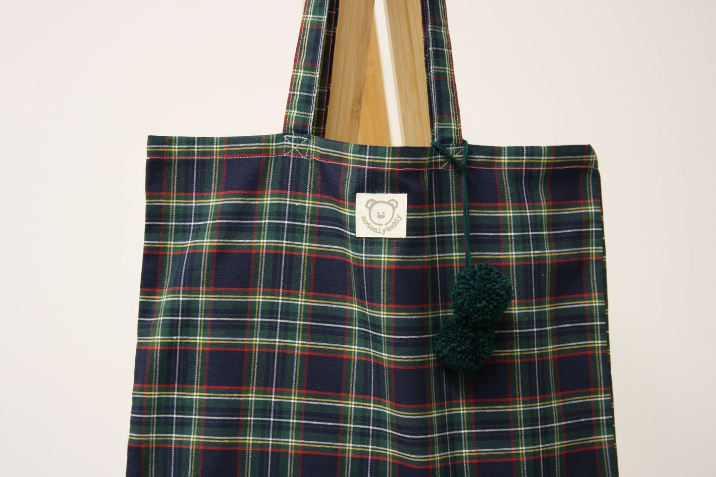 Dettaglio pom pon verdi su shopper donna scozzese blu
