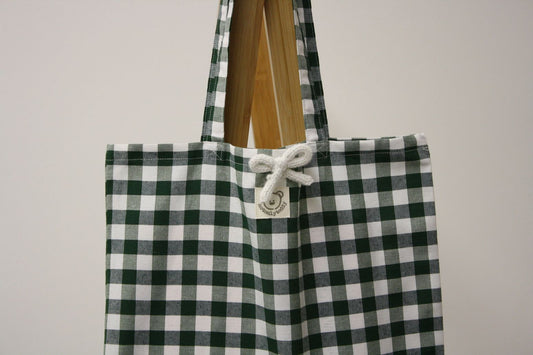 dettaglio spillina bianca su shopper in tela a quadri verdi
