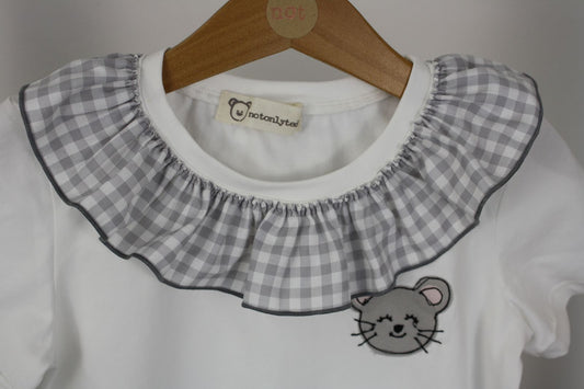 Dettaglio scollo di maglietta a maniche corte bianca per bambina con colletto arricciato in tessuto a quadretti grigi e ricamo di topolina